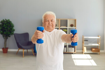 Senior man leading active lifestyle exercising with dumbbells in his living-room