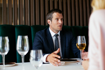 Handsome businessman dressed in the suit drinking wine. Businessman enjoying in the restaurant.