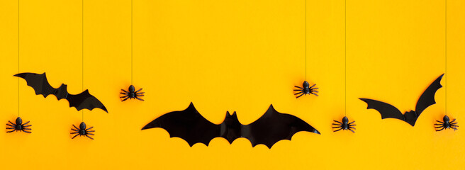 Banner for Halloween. Black spiders and bats on an orange background.
