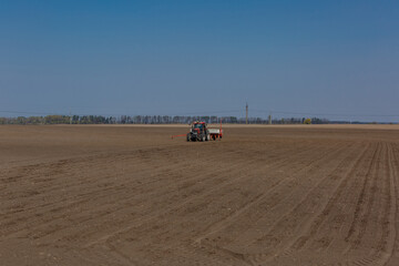 Tractor with sowing machine working on a field.  Seeding - sowing crops at agricultural fields in spring.