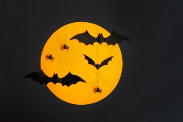 Halloween. Composition. Black bats and spiders against the orange moon and black background. Copy space.