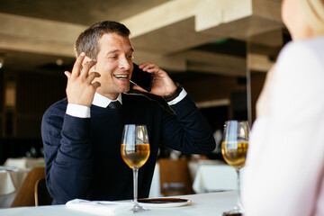 Handsome businessman dressed in the suit drinking wine. Businessman enjoying in the restaurant..