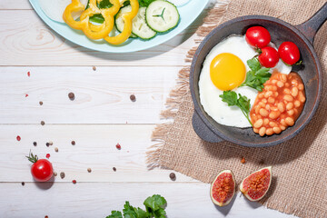 fried egg in cast iron serving pan, cherry tomatoes, beans and vegetables