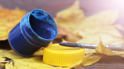 Bank of blue gouache and brush,autumn leaf background