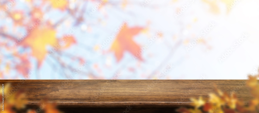 Poster autumn background.empty old rustic wood table with blur forest tree with sunlight,autumn fall backdr