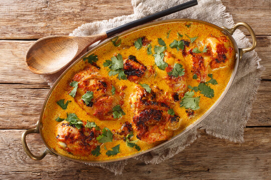 Kenyan Kuku Paka is a chicken roasted over charcoal and then cooked in a coconut curry closeup in the pan on the table. Horizontal top view from above