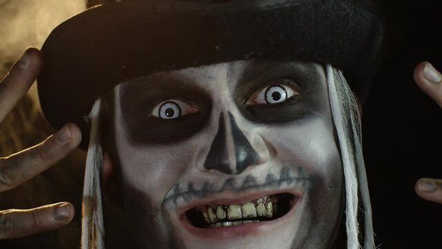 Man in skeleton Halloween cosplay costume. Guy in creepy skull makeup looking wide open eyes