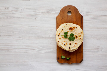 Homemade Roti Chapati Flatbread on a rustic wooden board, top view. Overhead, from above, flat lay. Copy space.