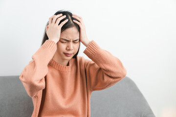 Tired young Asian woman sitting and have a headache because migraine.