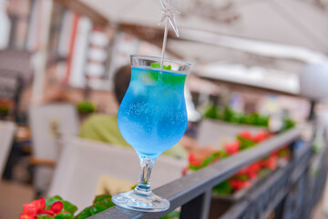 Three fresh juice drinks in tall glasses with plastic straws outside. Milkshake, blue curacao cocktail and mohito.