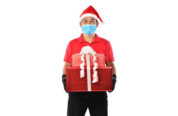 Happy Asian delivery man in red uniform, medical face mask, protective gloves, Christmas hat carry boxes of presents in the hands-on white background during COVID-19 outbreak and Christmas festivities