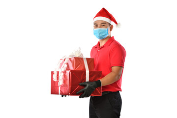 Happy Asian delivery man in red uniform, medical face mask, protective gloves, Christmas hat carry boxes of presents in the hands-on white background during COVID-19 outbreak and Christmas festivities