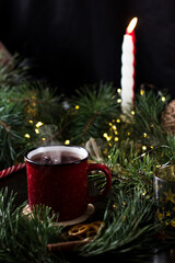 New year's tea party with spices. Red mug with tea surrounded by garlands, fir branches and spices	
