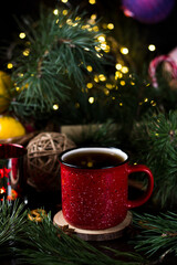 New year's tea party with spices. Red mug with tea surrounded by garlands, fir branches and spices	
