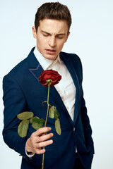 A man in a suit with a rose in his hands a gift date light background