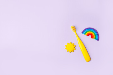 Yellow Cute kids toothbrush, sun, rainbow on pastel purple background. Dental and healthcare concept, copy space, 90s, 80s style design, bright flyer for dental clinic