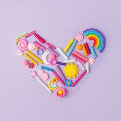 Heart from many kids accessories from clay, wax chalk on purple pastel background, Concept of pop art culture, abstract, 80s, 90s, creative design, nen plastic bold color experimental idea