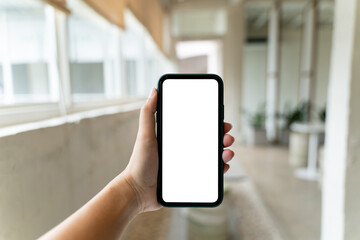 Hand holding empty screen smartphone at coffee cafe.