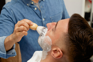 Barber preparing client to shave beard
