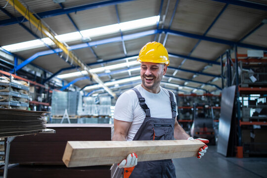 Factory worker carpenter holding wood material and working in furniture industry.