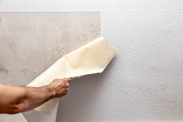 soaked wallpaper is peeled off the wall by a craftsman