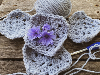 crocheted fragments and flowers on wooden background