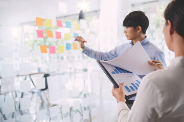 Business people brainstorming putting sticky note on glass wall, Selected focus.