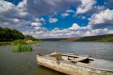 Obraz premium Old metal fishing boat moored in the shallow waters of the river