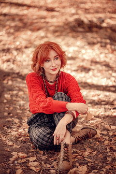 Autumn portrait of a red-haired woman with sitting on the graund 