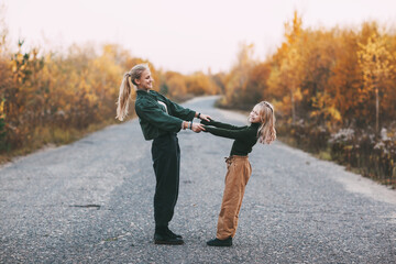 Obraz premium Happy mature mom and her blonde little daughter hugging and laughing while walking in autumn park outdoors