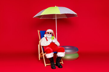 Portrait of his he nice handsome bearded fat Santa sitting in chair using gadget roaming service...