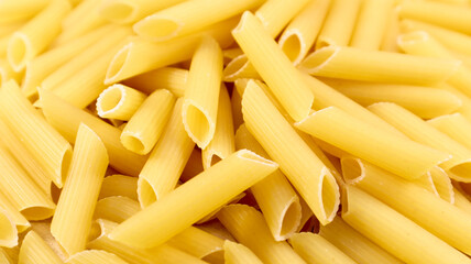 Penne Rigate Raw Pasta is a short pasta with oblique cuts and a ribbed surface. Traditional Italian pasta. Pasta background. Italian food ingredient top view.
