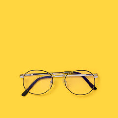 Eyeglasses on a yellow background. Minimalistic concept with copy space.