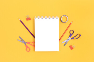 Notepad mockup with stationery on a bright yellow background. Back to school concept.