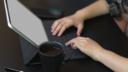 Fototapeta na wymiar Female hands typing on tablet keyboard on black table