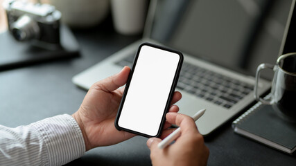 Male using mock up smartphone while sitting at worktable