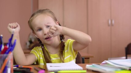 A beautiful little girl sits at the table and counts her fingers on her hand. Preschool education. 4k