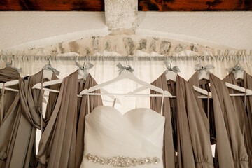 Close-up of the bride's wedding dress against the background of the bridesmaid dresses on the cornice.