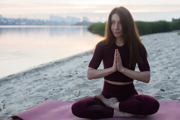 Young woman doing Hatha yoga on the beach in the morning. Outdoor meditation
