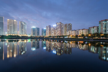 Buildings with reflections on lake at twilight at Thanh Xuan park. Hanoi cityscape at twilight period