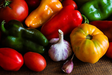 Colorful vegetables background. Harvest. Fresh raw sweet peppers, tomatoes and garlic on wooden background. Concept of healthy food, detox. Selective focus