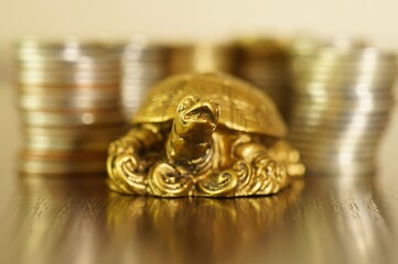 A metal turtle next to a stack of coins. Symbol of financial well-being.