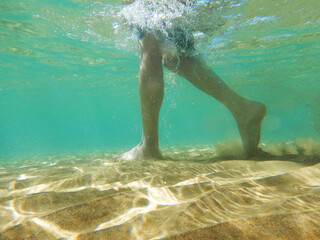 Underwater shot of male legs walking on sea bottom 