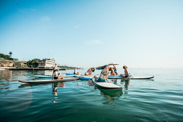 Young woman doing Pilates on a SUP board in the lake at sunrise