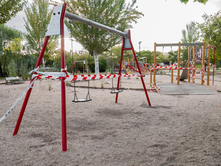 Swings and public parks closed with plastic tapes with the text: "do not pass" "forbidden to pass" due to the ban in the community of Madrid due to the coronavirus in San Sebastián de los Reyes