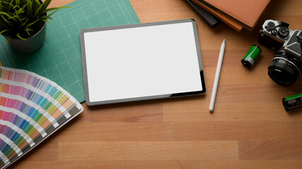 Mock up digital tablet on wooden table with camera, supplies and copy space