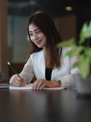 Female office worker working with stationery on table in office room