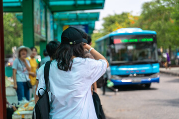 Asian young girl wear hat waiting for bus at bus stop
