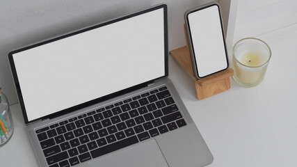 Mock up laptop computer and smartphone on white table in workspace