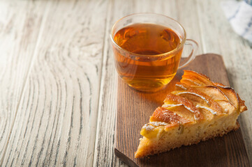 Heap of homemade apple pie close-up and copy space. A quick autumn dessert idea with tea. Autumn pie with apples, Rustic wooden background.
